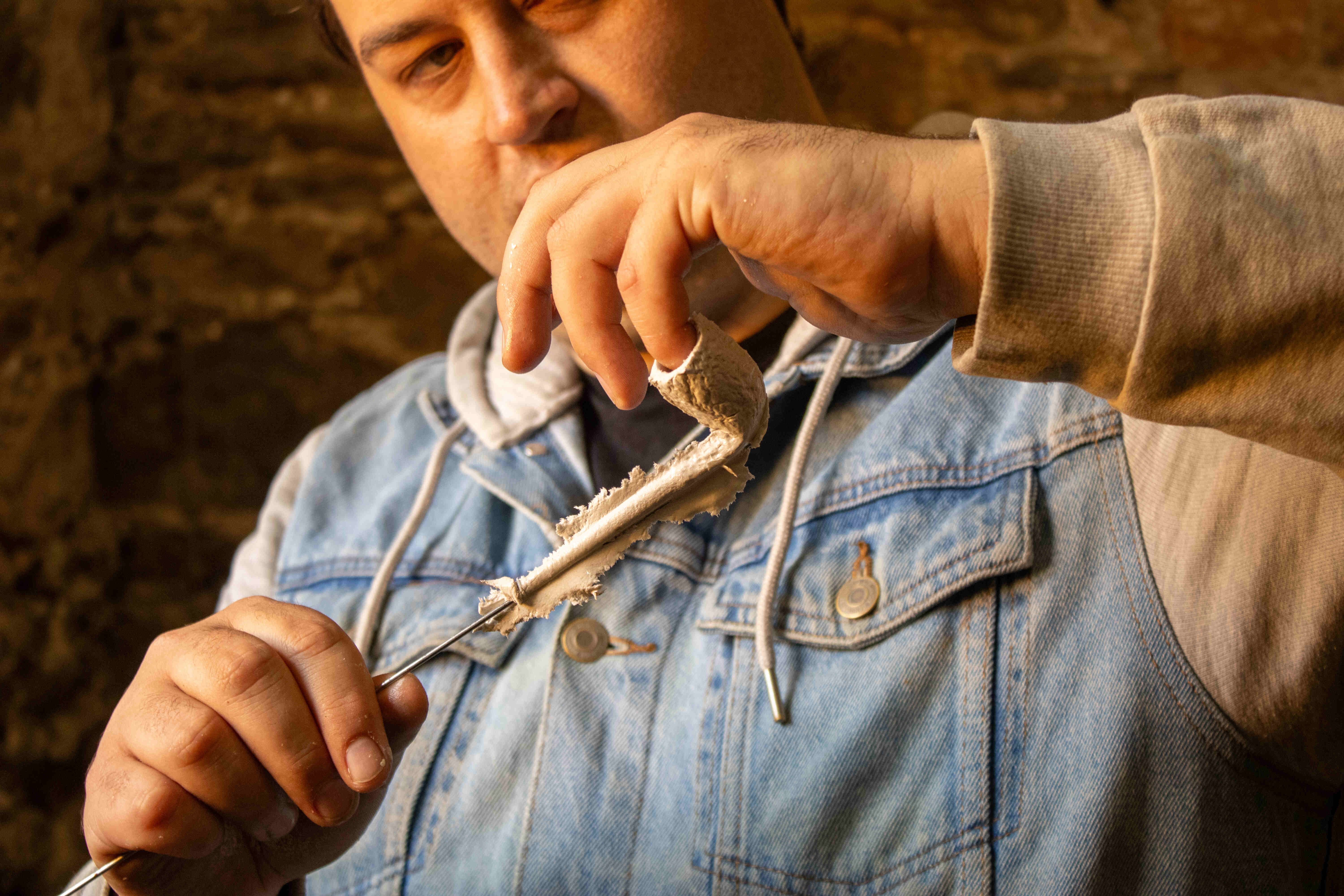 Closeup image of a person holding a newly made clay tobacco pipe.